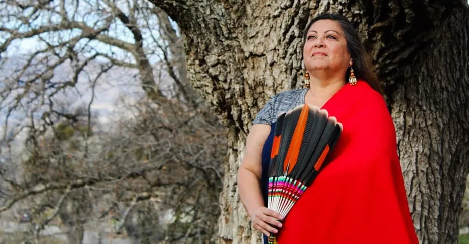 Jacquie Garza Lawrence seated outdoors in a red shawl.